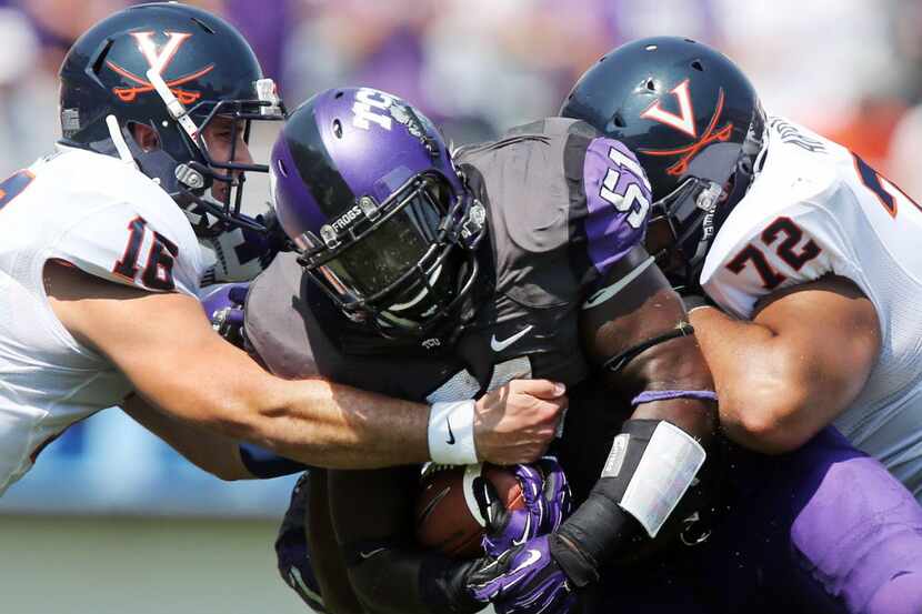 TCU linebacker Kenny Cain (51) is tackled by Virginia quarterback Michael Rocco (16) and ...