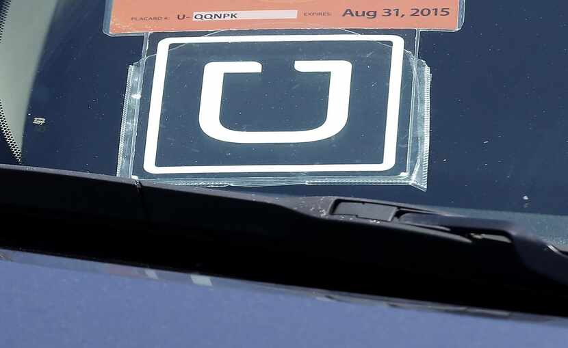 In this Wednesday, July 15, 2015, file photo, an Uber sign is displayed on a driver's car...