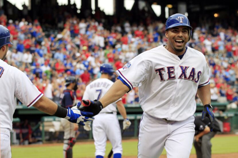 Texas Rangers right fielder Nelson Cruz (17) happily slaps hands with a teammate at home...