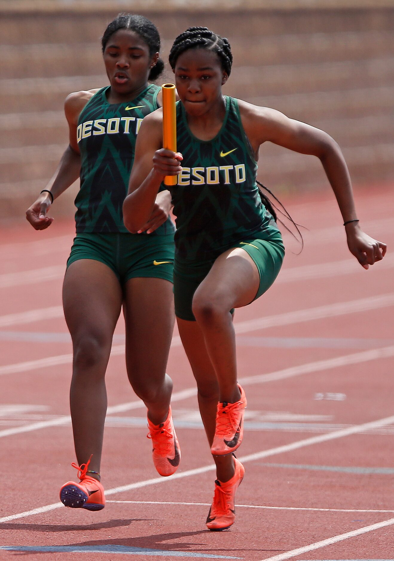 Mia Abraham (left) hands off to Trinity Kirk as they compete for DeSotto High School in the...