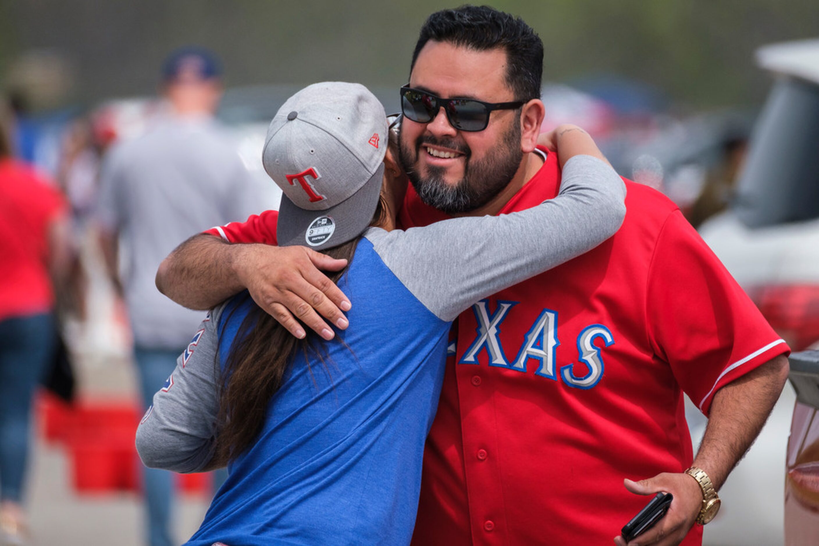 Jacki Gutierrez hugs her friend Julio Garza as the meet in the parking lot while tailgating...