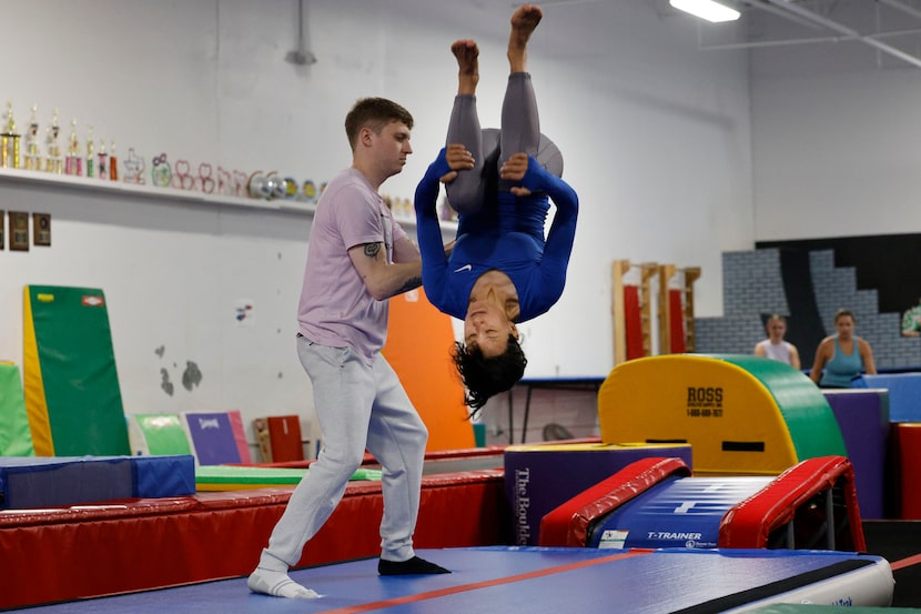 Corinne Gonzalez, 42, of Irving does a back flip as Caegan Arvidson, recreation director of...