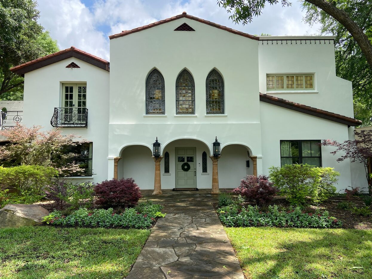 This 1930s Spanish Eclectic features seasonal flowerbeds that flank the entrance of the...