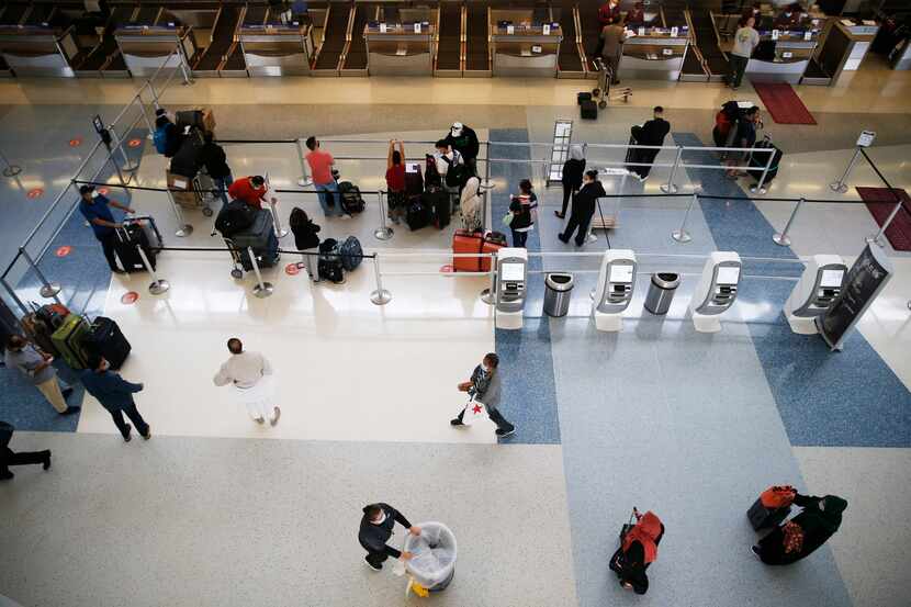 Travelers wait to check their bags in the Qatar Airways line of Terminal D at DFW...