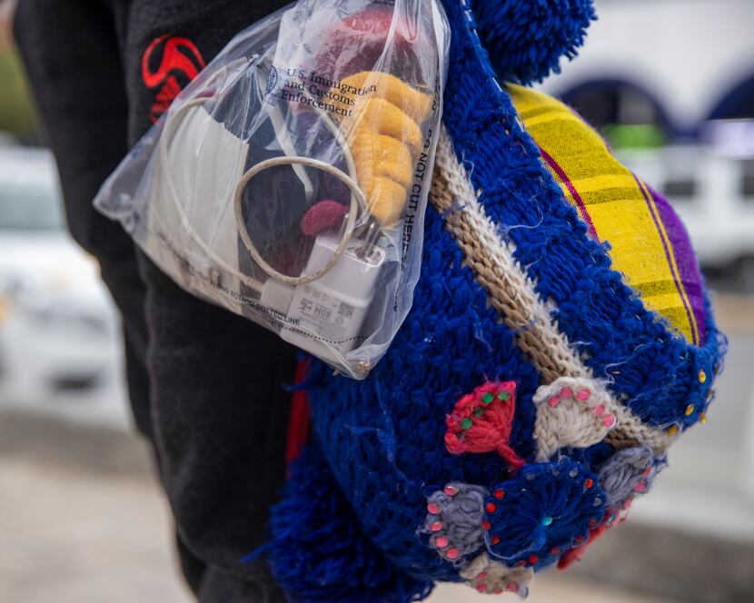 Isabela Julaj holds her few belongings in a U.S. government-provided plastic bag and a knit...
