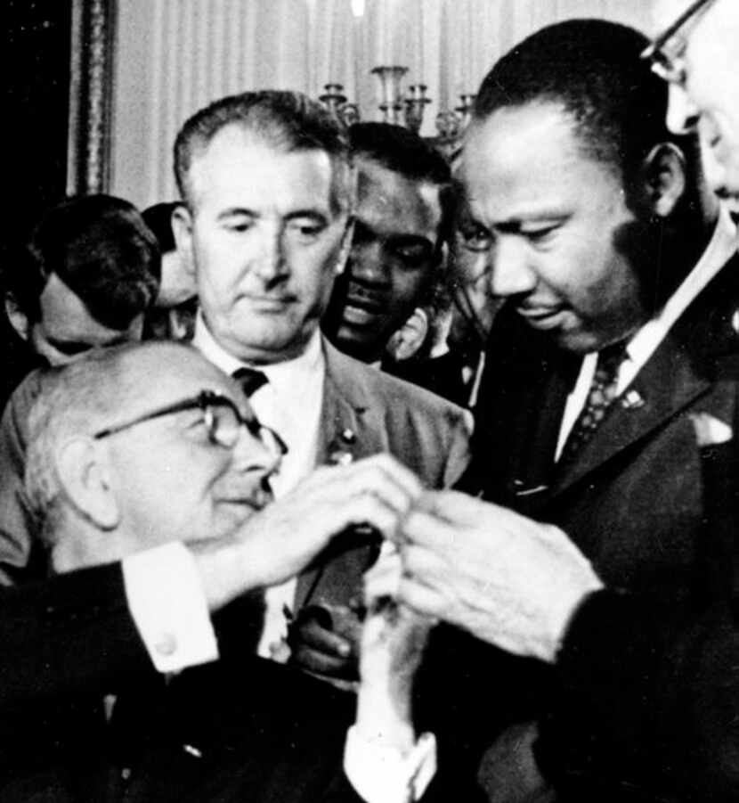 
President Lyndon B. Johnson reached to shake hands with the Rev. Martin Luther King Jr. at...