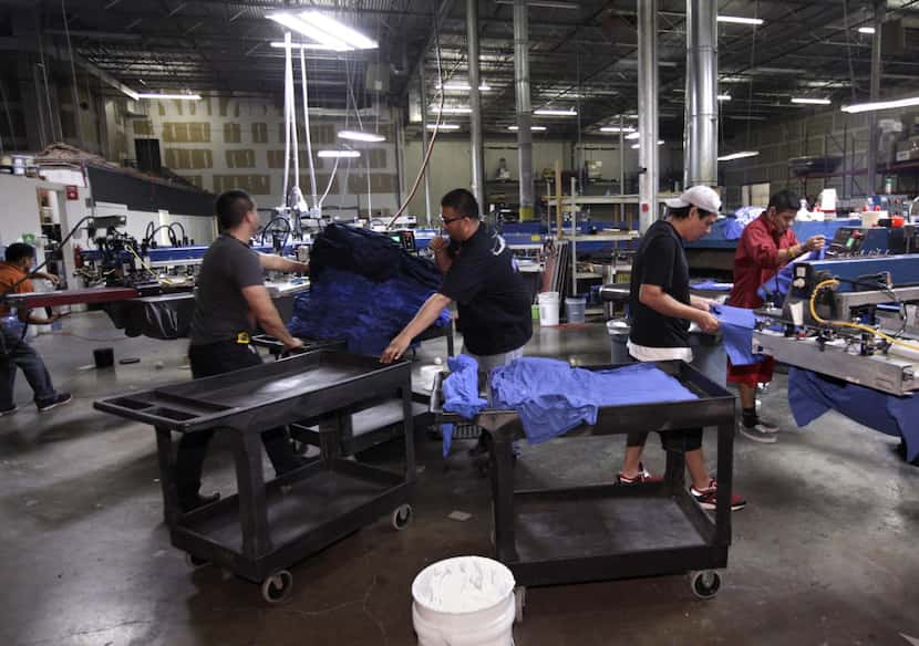 Workers produce NCAA championship t-shirts through the night at Pony Xpress Printing in...