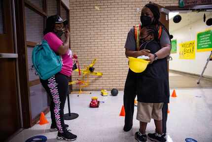 Mom Chequetta Shed (left) watches as Principal Shanieka Christmas-McDonald hugs her son...