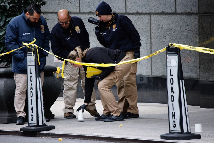 Members of the New York police crime scene unit pick up cups marking the spots where bullets...