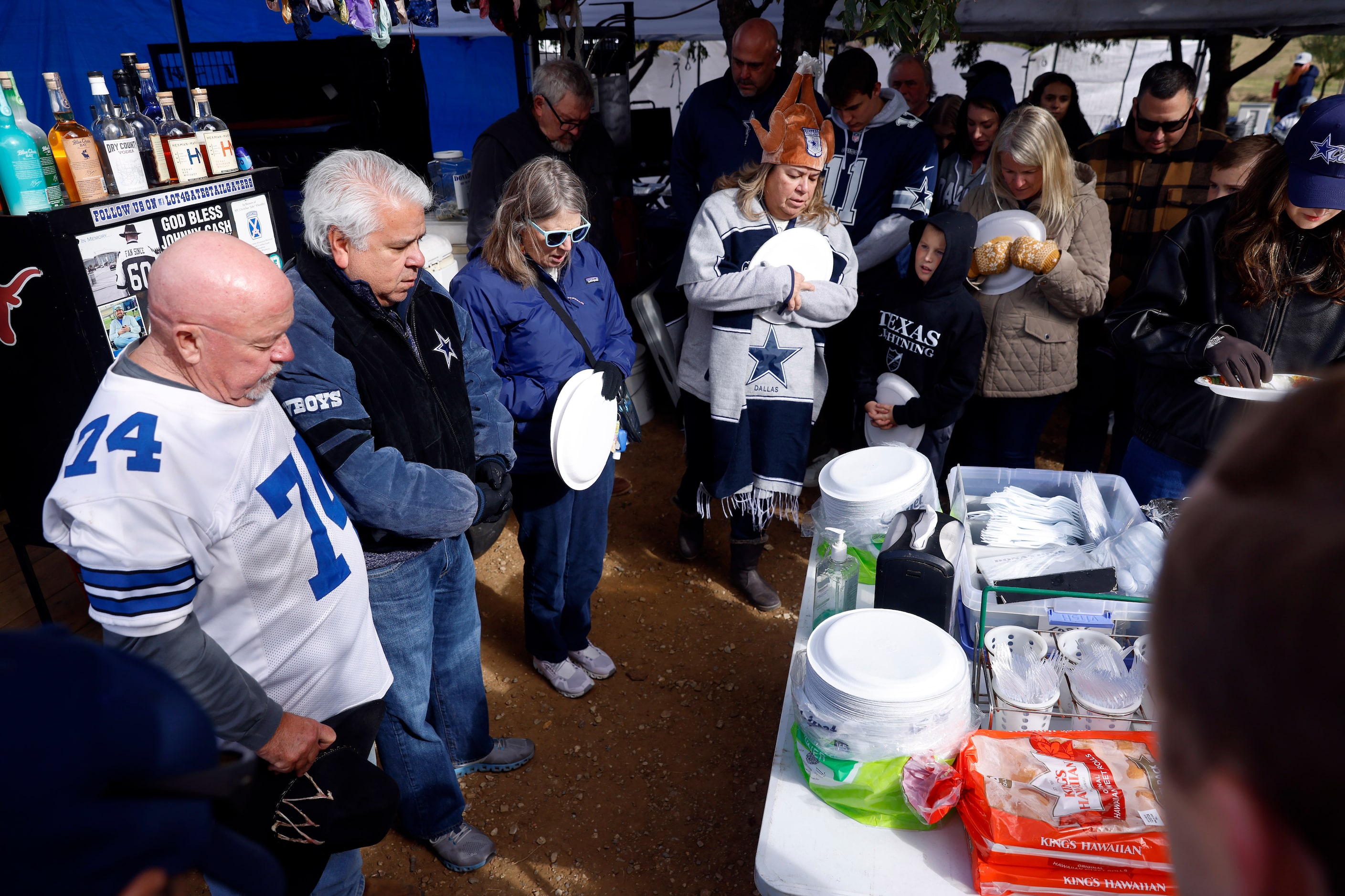 Dave Armendariz (second from left) leads a prayer before Cowboys fans eat a Thanksgiving Day...