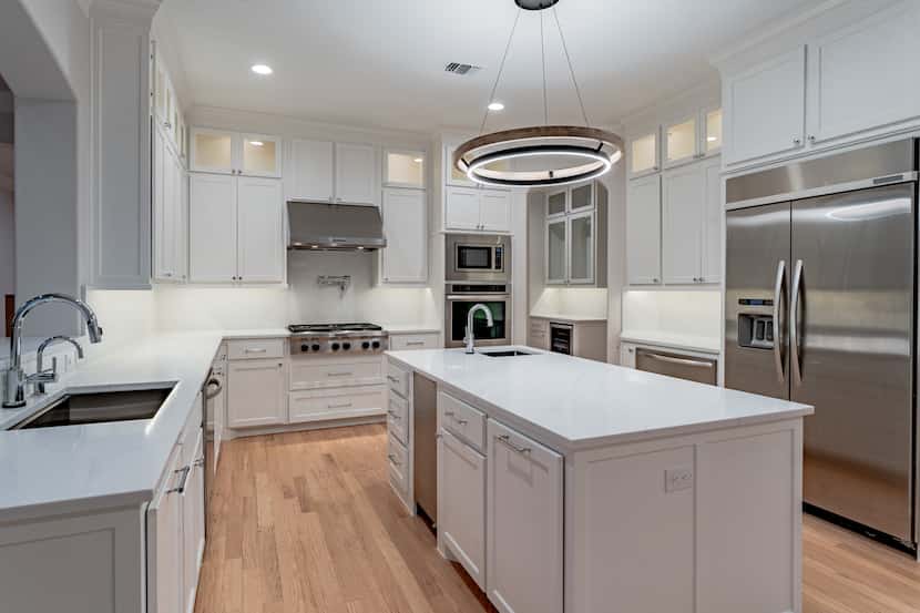 A white kitchen features new appliances and a beautiful island.
