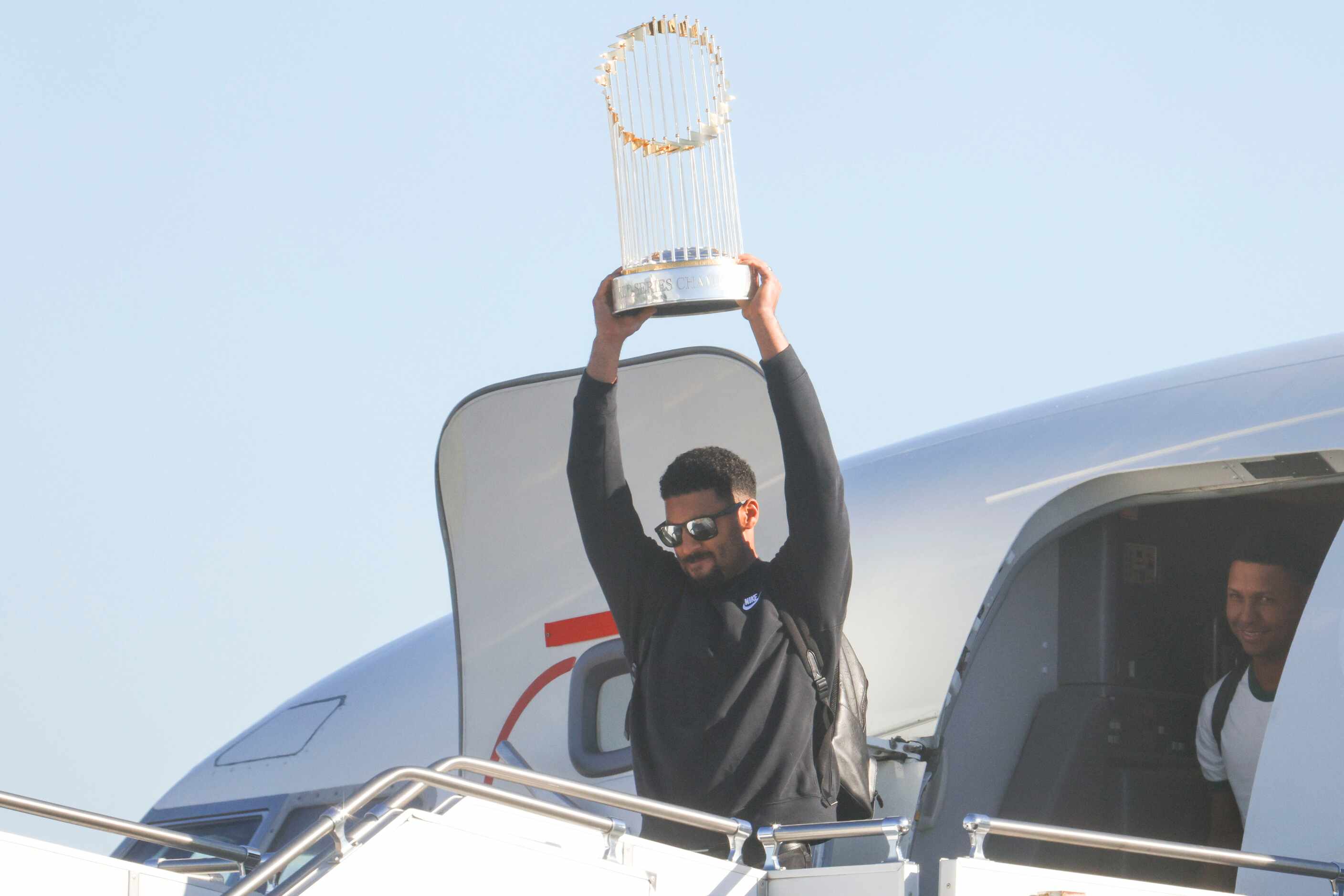 Texas Rangers’ Marcus Semien hoists the Commissioner's Trophy by pitcher José Leclerc upon...
