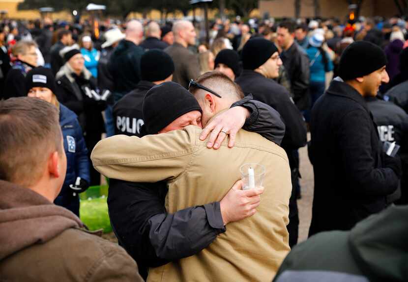 Fellow Richardson police officers console one another before a vigil held for slain...