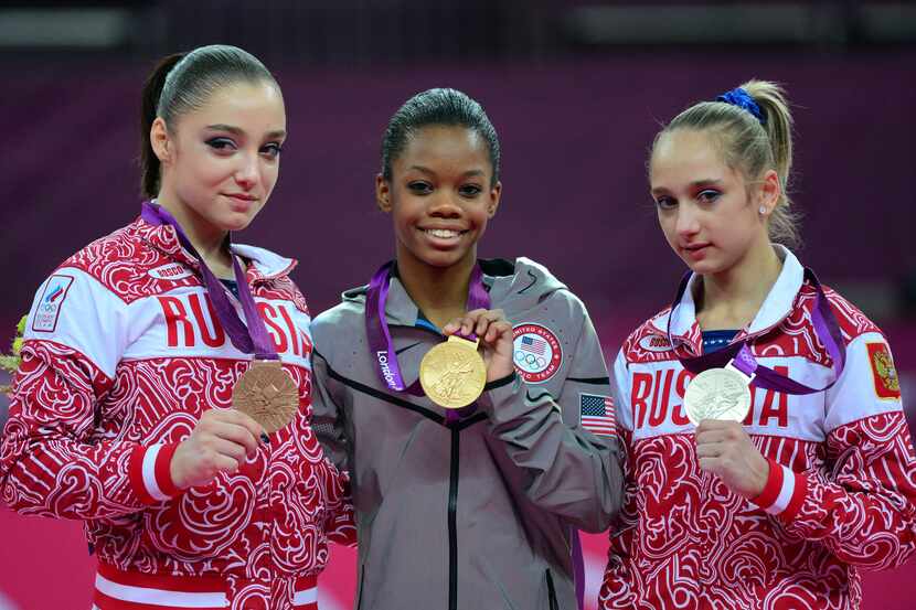 US gymnast Gabrielle Douglas (center) poses on the podium with Russia's gymnast Victoria...