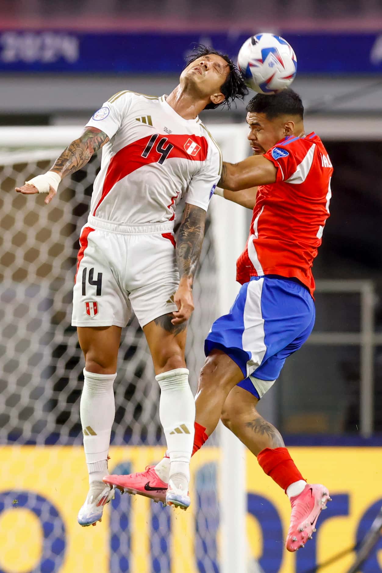 Peru forward Gianluca Lapadula (14) and Chile defender Paulo Díaz (5) jump to head the ball...