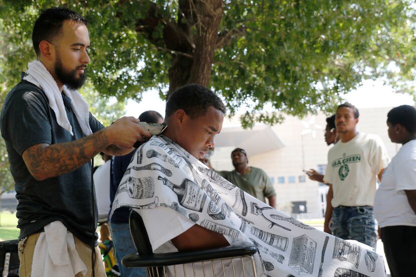 Michael Jacinto, owner of Wise Guys Old School Barber Shop in Cedar Hill, gives a haircut to...
