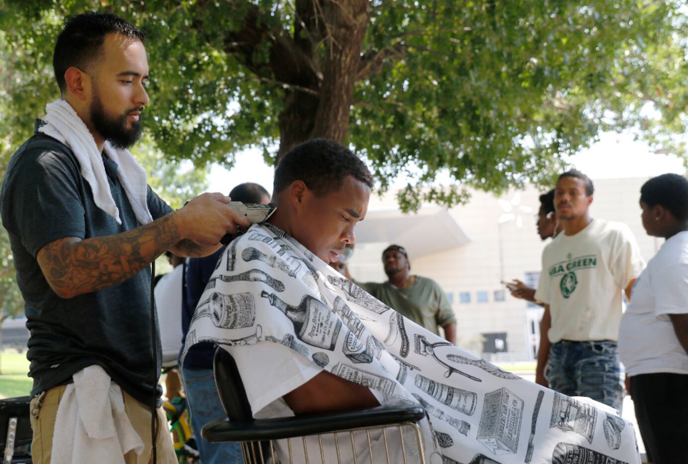 Michael Jacinto, owner of Wise Guys Old School Barber Shop in Cedar Hill, gives a haircut to...
