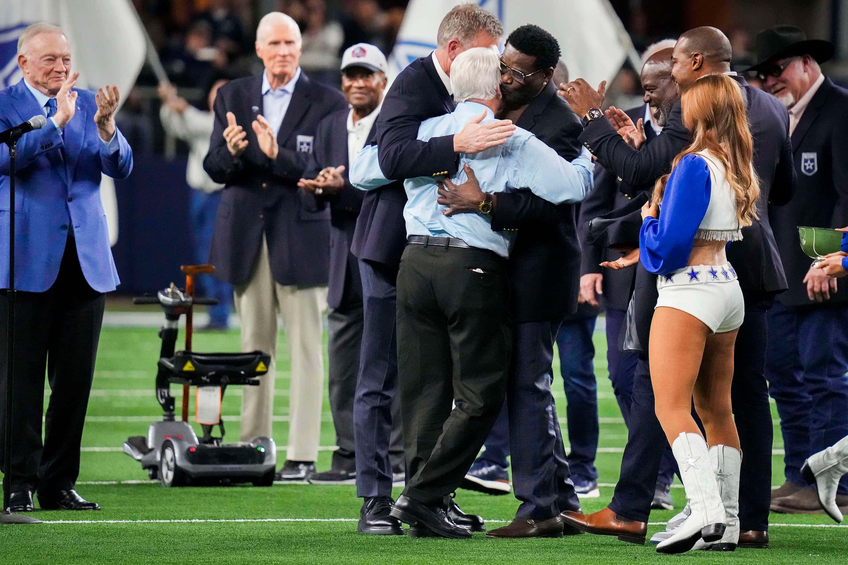 Former Dallas Cowboys head coach Jimmy Johnson hugs former players Troy Aikman and Michael...