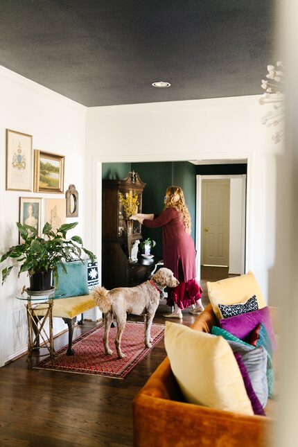 The back of a living space with a gallery wall, yellow velvet bench and a red runner