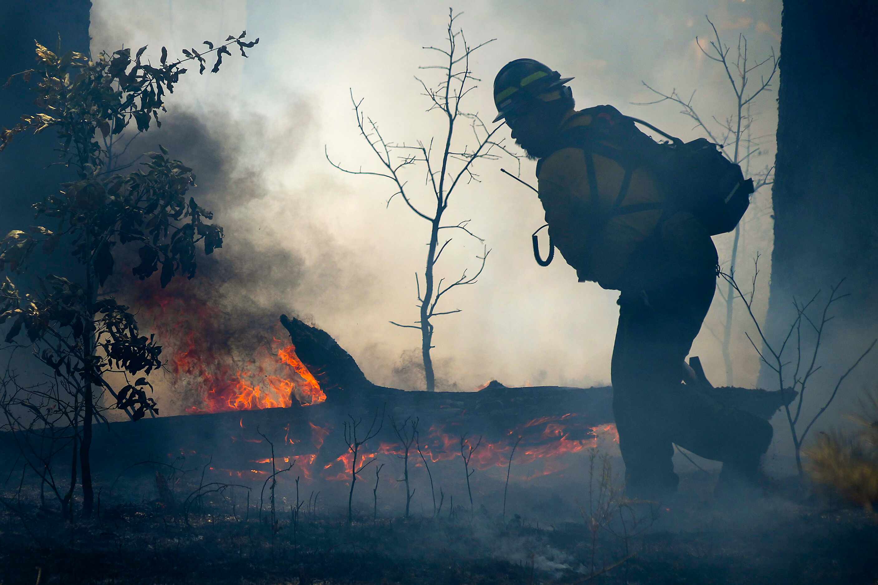 Mykiah Williams of the Alabama-Coushatta Wildland Fire Management team moves a burning log...