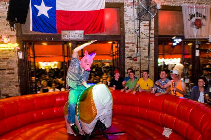 Martin Daley of Dallas wears a pig mask and rides a mechanical bull at The Trophy Room on...