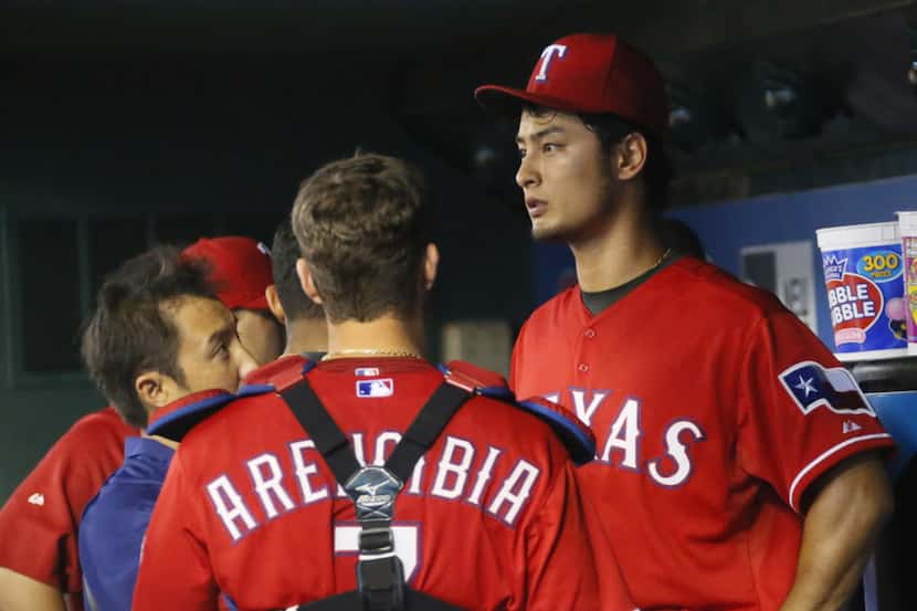 Texas pitcher Yu Darvish talks with teammates in the dugout in the top of the ninth inning...