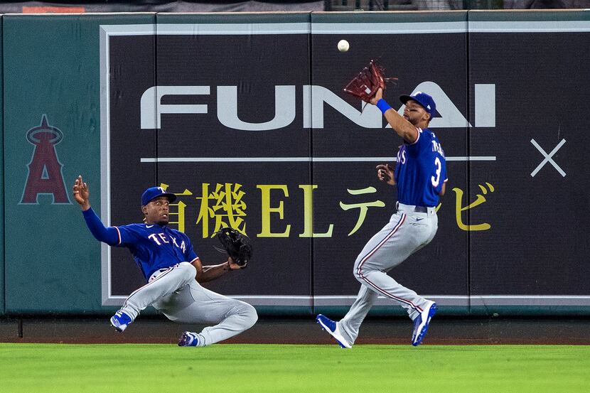 Texas Rangers center fielder Leody Taveras, right, catches a fly ball hit by Los Angeles...