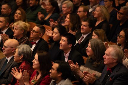 Audience members smile and applaud.