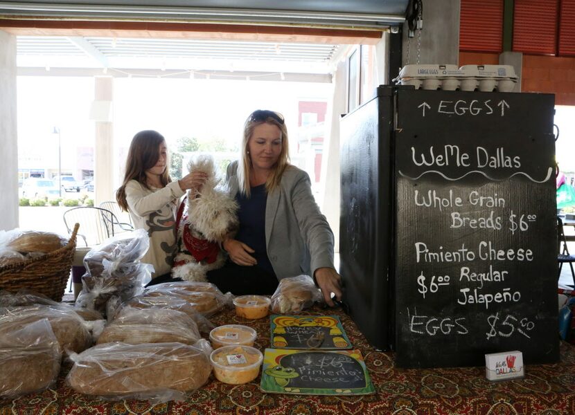 WeMe (CQ) owner Christine Carey plays with a vendor's dog at the Grand Prairie Farmers...