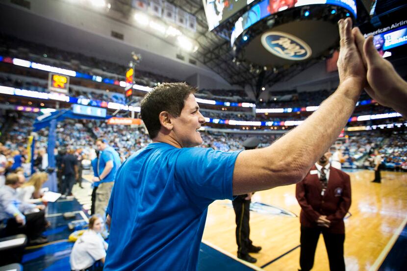 Dallas Mavericks owner Mark Cuban high fives courtside fans before an NBA basketball game...