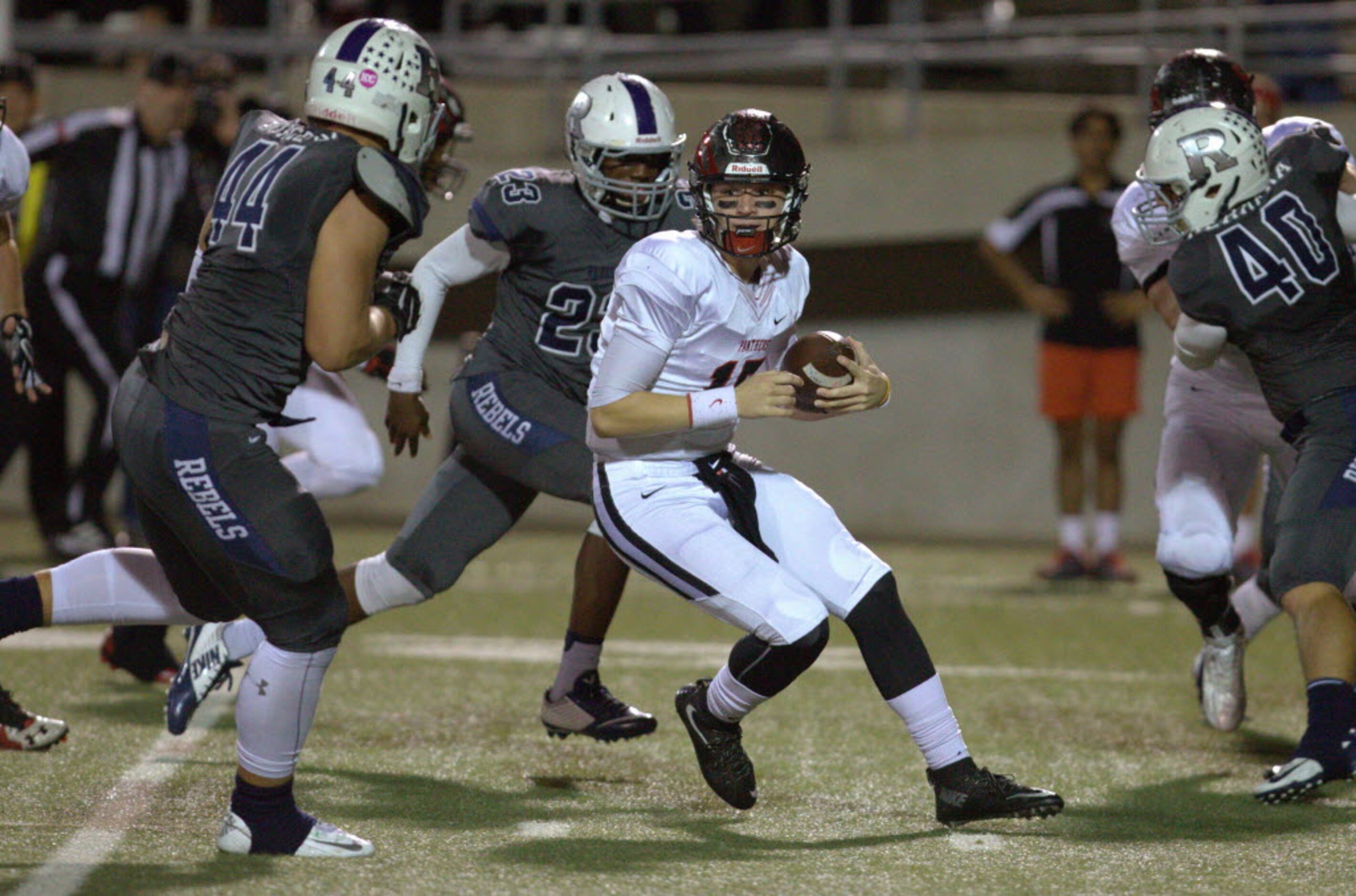 Colleyville Heritage junior quarterback Camden Roane, center, looks for room against...