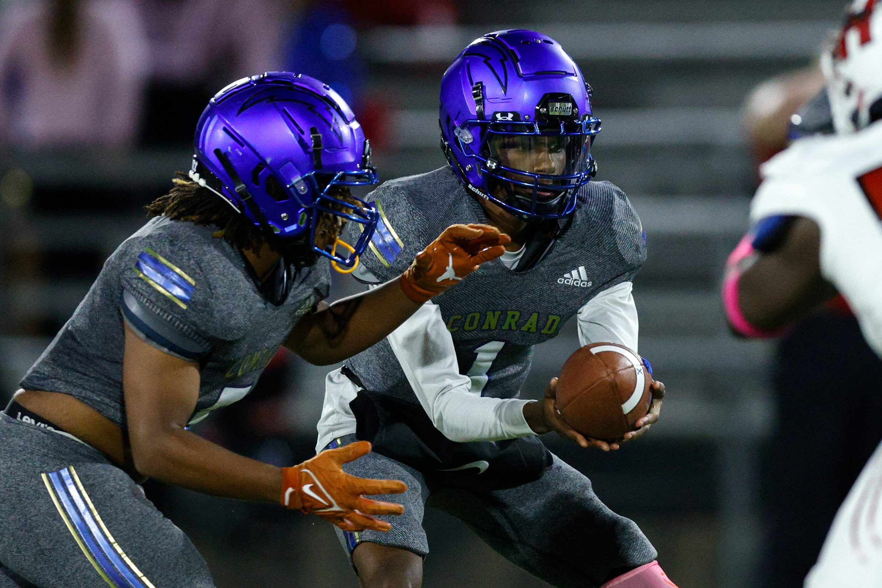 Conrad quarterback Ladavian Frost-Harris (1) hands the ball to running back Ashton Ross (7)...