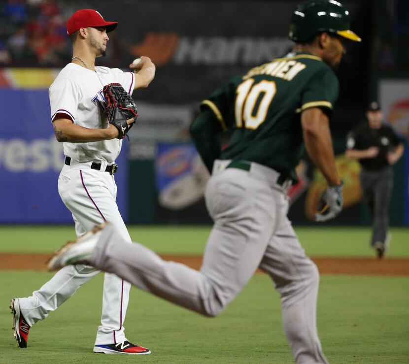 Texas Rangers relief pitcher Alex Claudio (58) throws out Oakland Athletics shortstop Marcus...