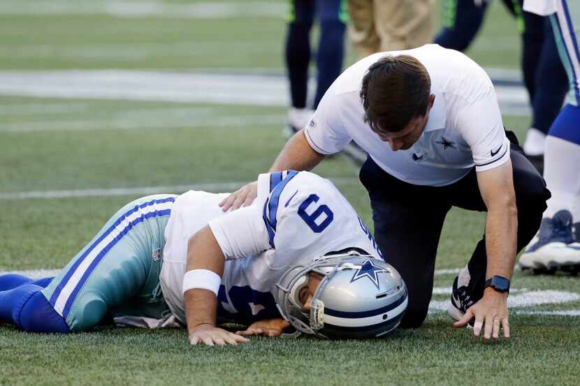 Dallas Cowboys quarterback Tony Romo is tended to by a trainer after he went down on a play...