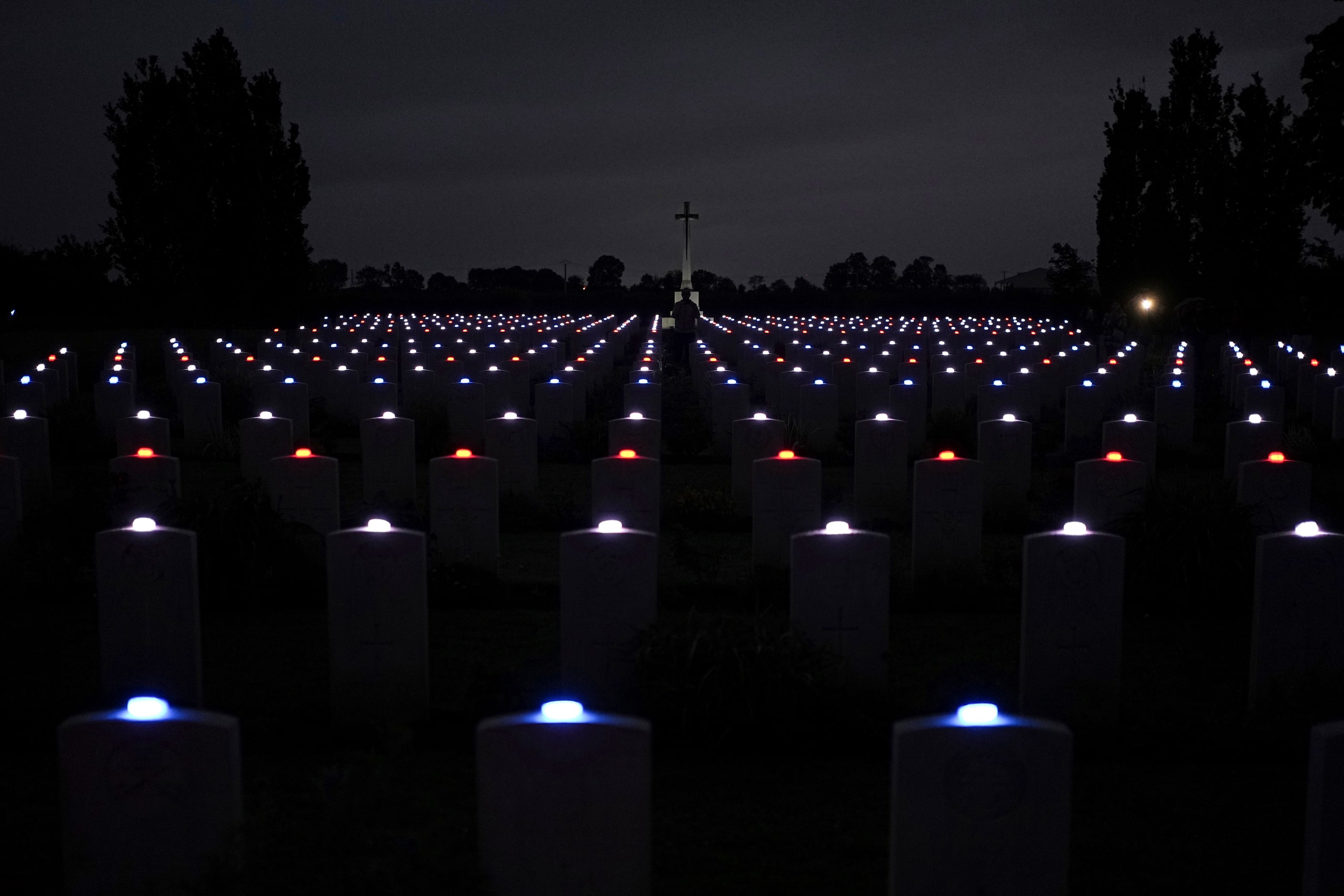 Candles are lit on each tombstone of the Commonwealth war cemetery of...