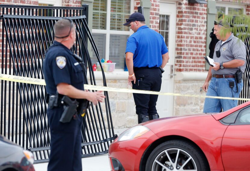 Police look at a downed section of fence after a vehicle crashed through it Thursday...