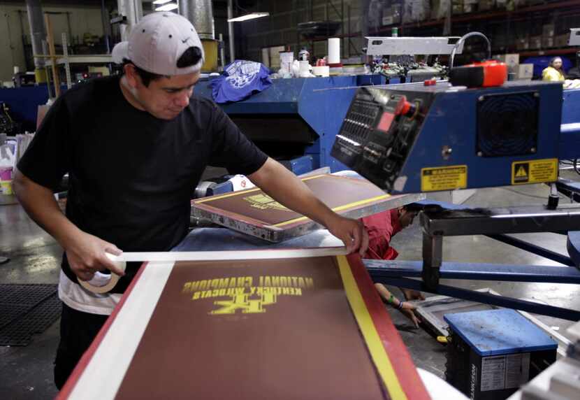 Nery Herrera prepares a screen to produce NCAA championship t-shirts proclaiming Kentucky as...