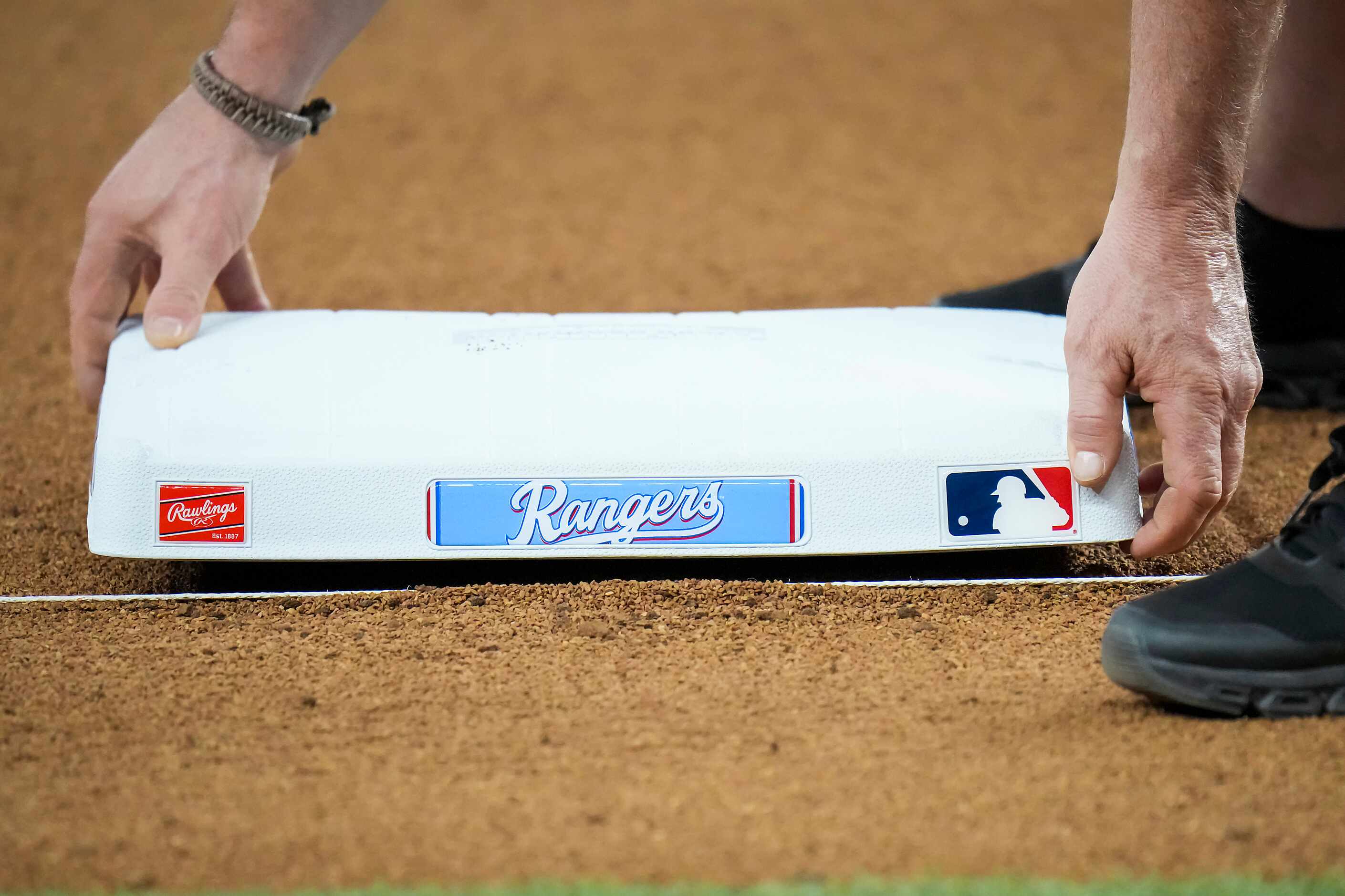 Groundskeepers set bases before an exhibition baseball game between the Texas Rangers and...