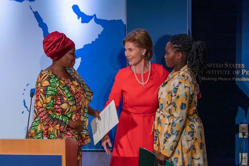Former first lady Laura Bush greets AIDS patient Tatu Msangi, left, and her daughter Faith...