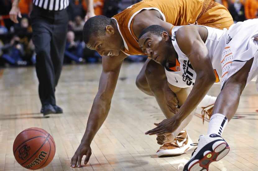 Texas forward Jonathan Holmes (10) and Oklahoma State's Markel Brown (22) dive for a loose...