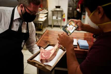 Mike Chen records a video as Luke Smithson presents his cut of steak at BAR-Ranch Steak...