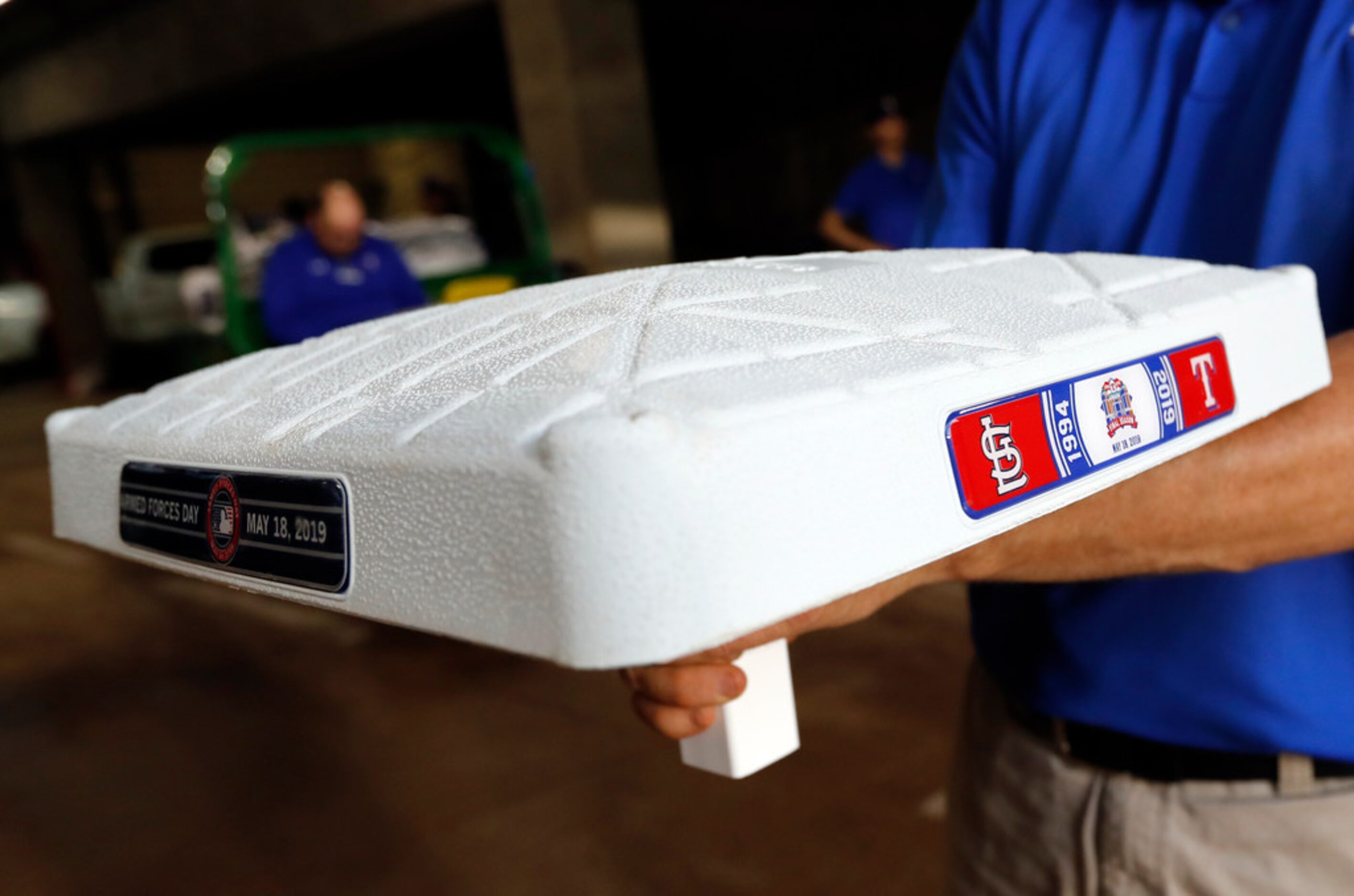 John Wilson, a member of the Texas Rangers grounds crew, holds up one of the bases to be...