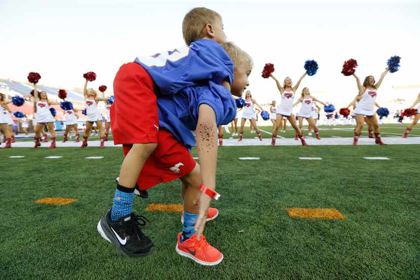 Luke Stigall, 6, lifts his brother Eli Stigall, 4, before the Southern Methodist Mustangs...