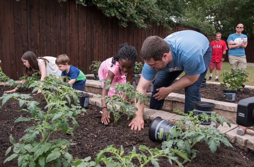 Austin Street Center's Daniel Roby (right) helps his daughter, Banner, plant seedings after...