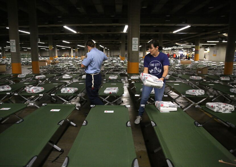 Volunteer Suzanne Ramirez distributes American Red Cross blankets onto beds to house up to...