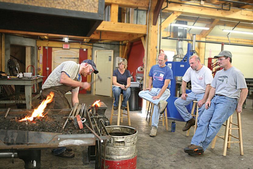 Blacksmithing students watch an instructor at work at John C. Campbell Folk School in...