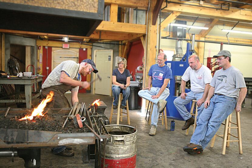 Blacksmithing students watch an instructor at work at John C. Campbell Folk School in...
