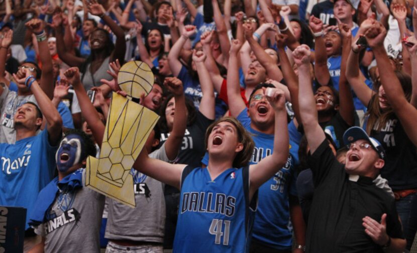 Kevin Gonzalez, left, and Ricky Pacheco, center, cheer as the Mavs run the clock out to win...