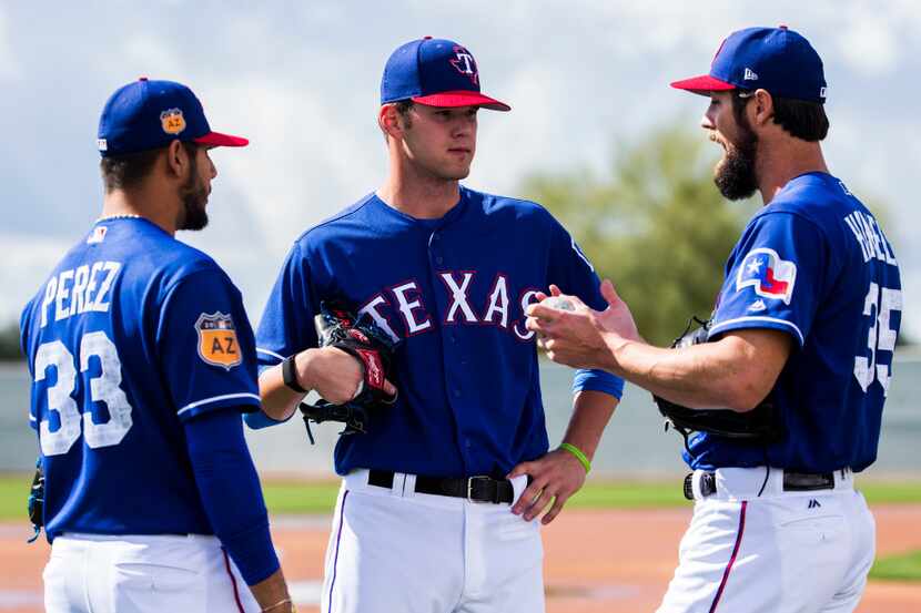 Minor league pitcher Cole Ragans, center, gets advice from starting pitchers Martin Perez...
