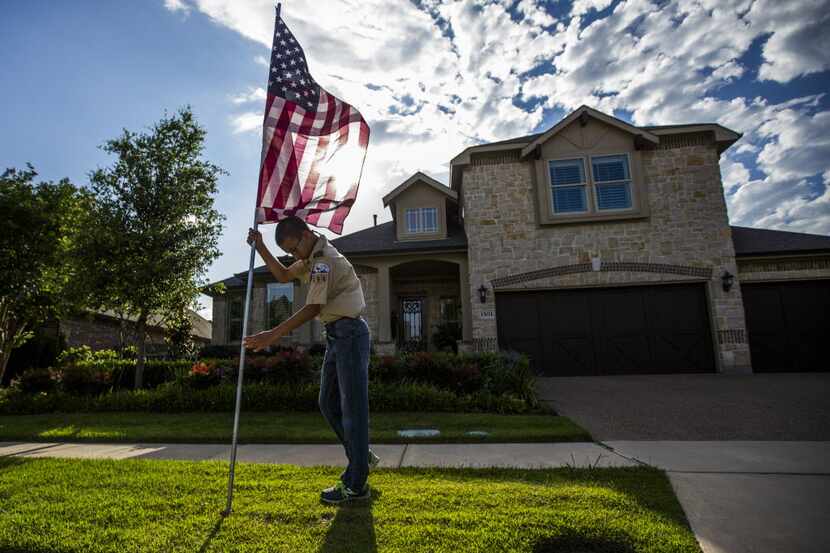 Boy scout Zach Plyler, 13, posts an American flag at a home on Thornberry Drive on Thursday,...